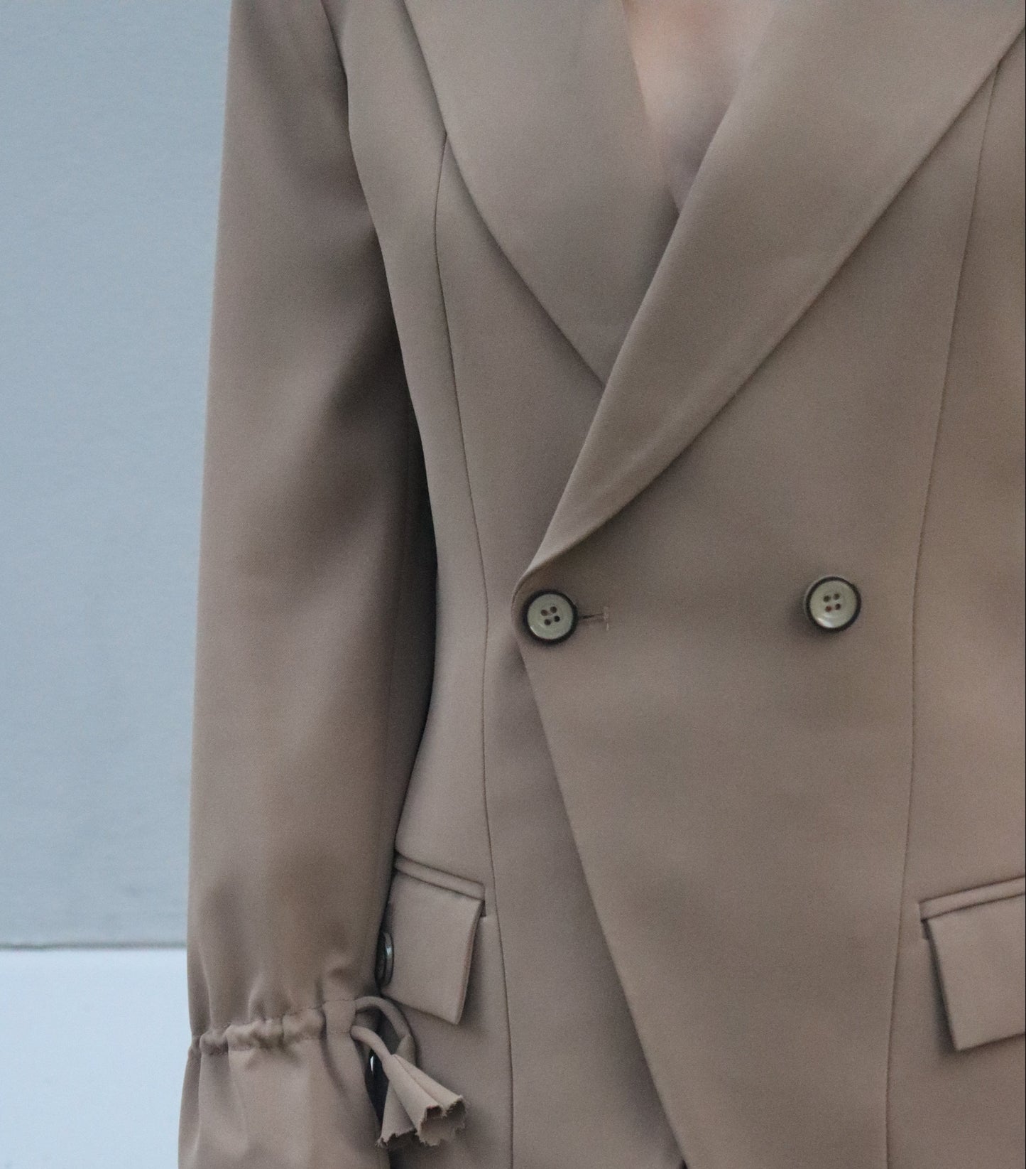 Close-up of a beige trench coat with a blurred background